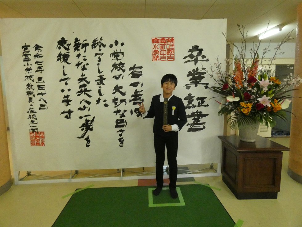 巨大卒業証書で写真撮影する様子